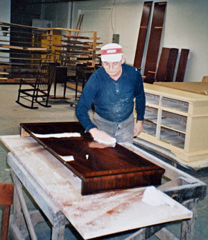 Polishing a mahogany table leaf before delivering it to a customer